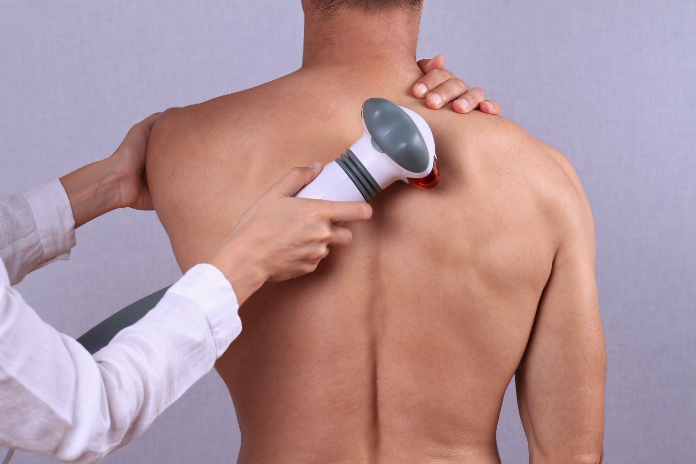 A person receiving treatment on their back with a handheld device