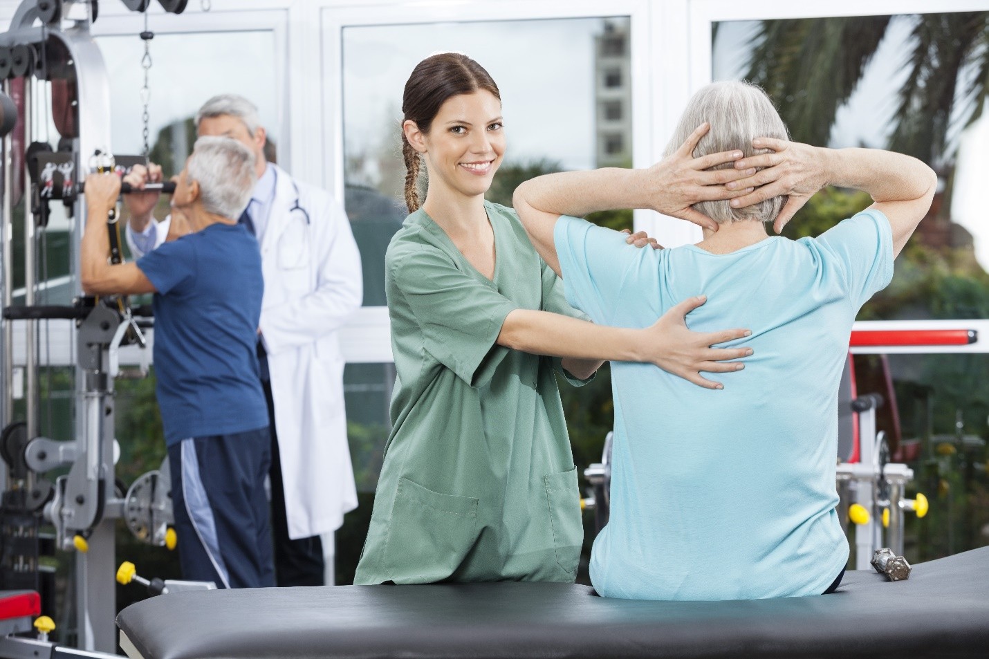 A physiotherapist assisting an elderly patient with back exercises in a rehabilitation center
