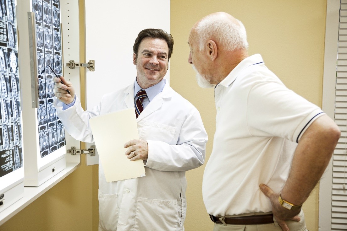 A doctor pointing to an X-ray while talking to a patient