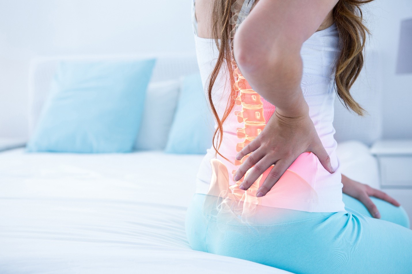 Woman holding her lower back with a spine overlay highlighting pain