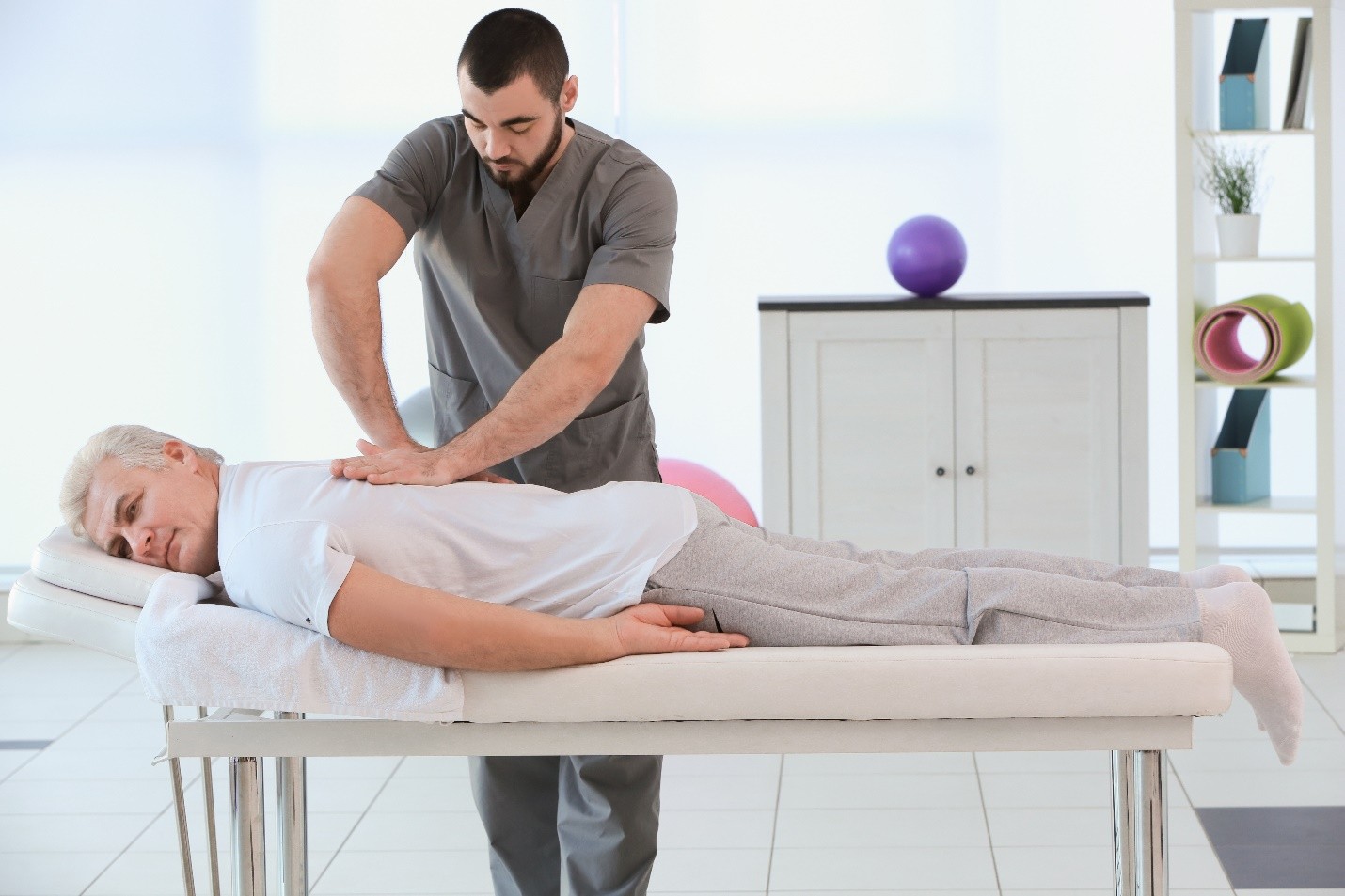 A healthcare professional performing a back adjustment on a patient lying face down on a treatment table