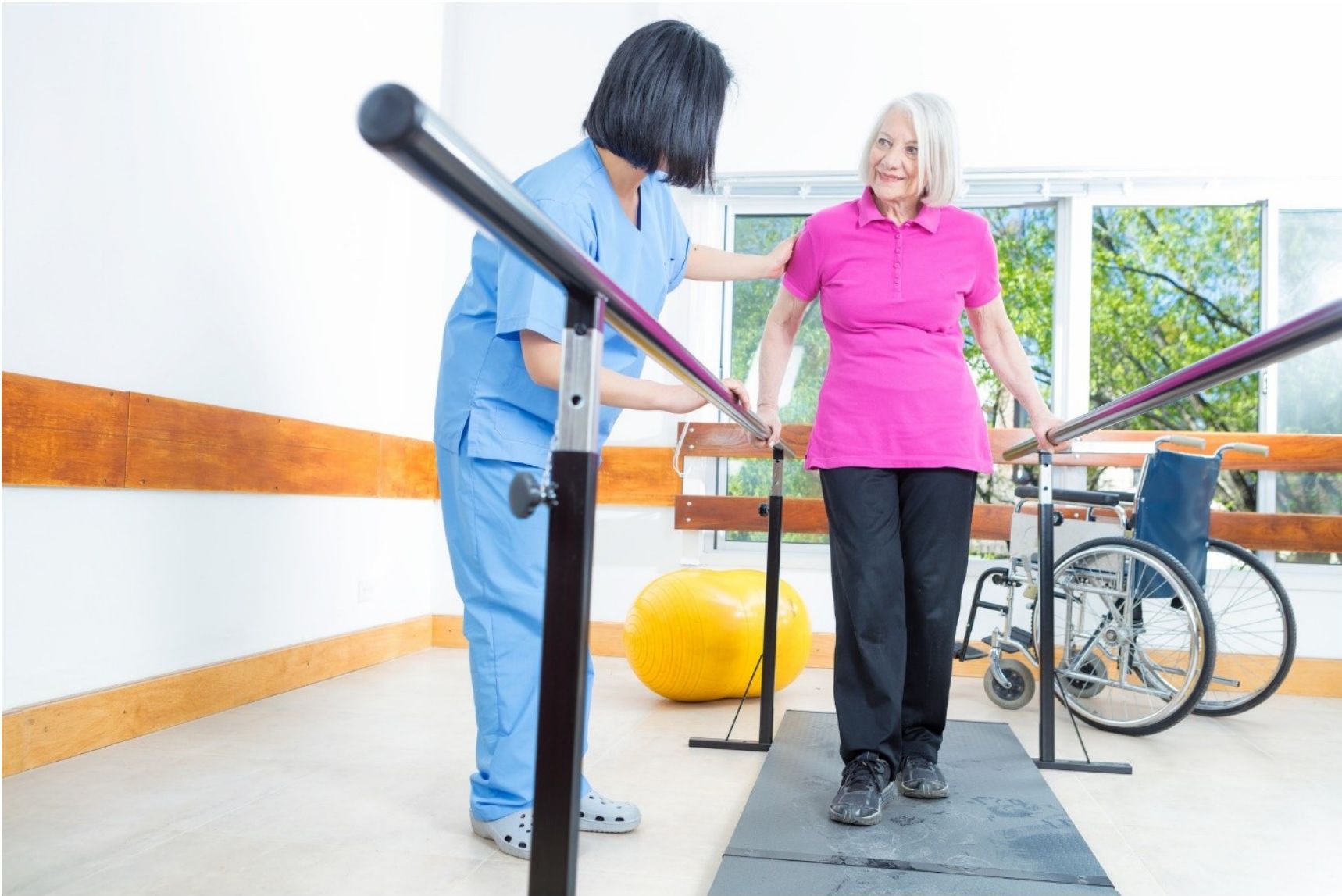 A healthcare professional assisting an elderly patient with walking exercises outdoors