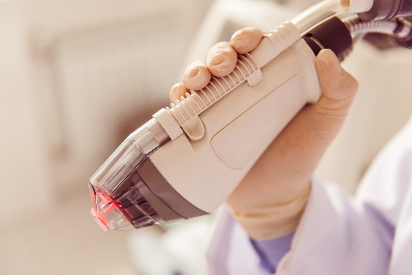 Close-up of a hand holding a medical device emitting red light