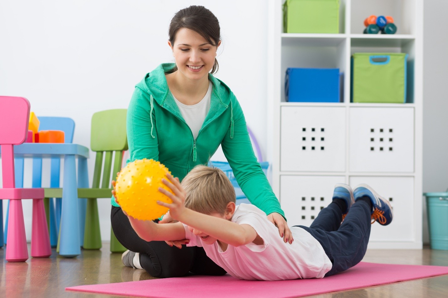 Therapist assisting a child with a stability ball