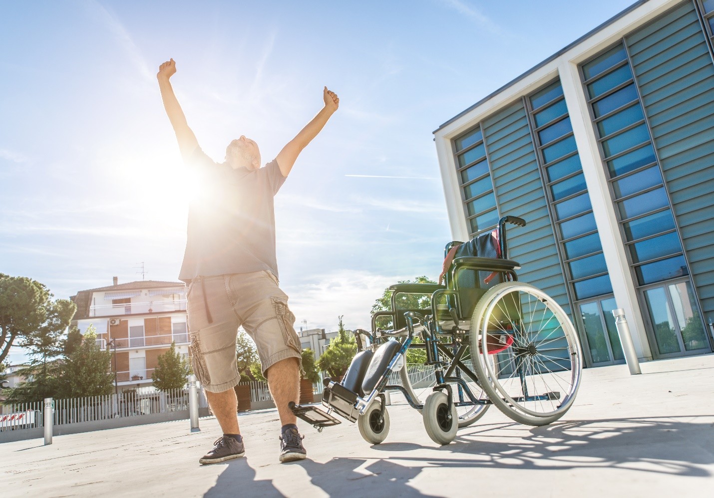 A man with his arms raised in celebration next to a wheelchair