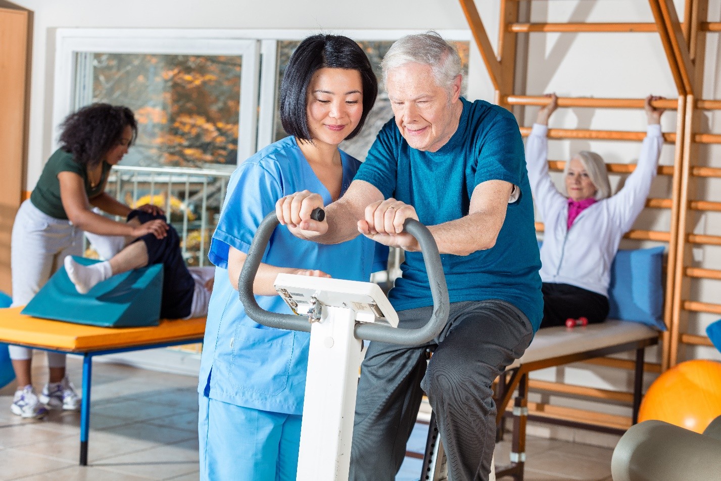 Physiotherapist assisting a patient on a stationary bike in a rehab centre